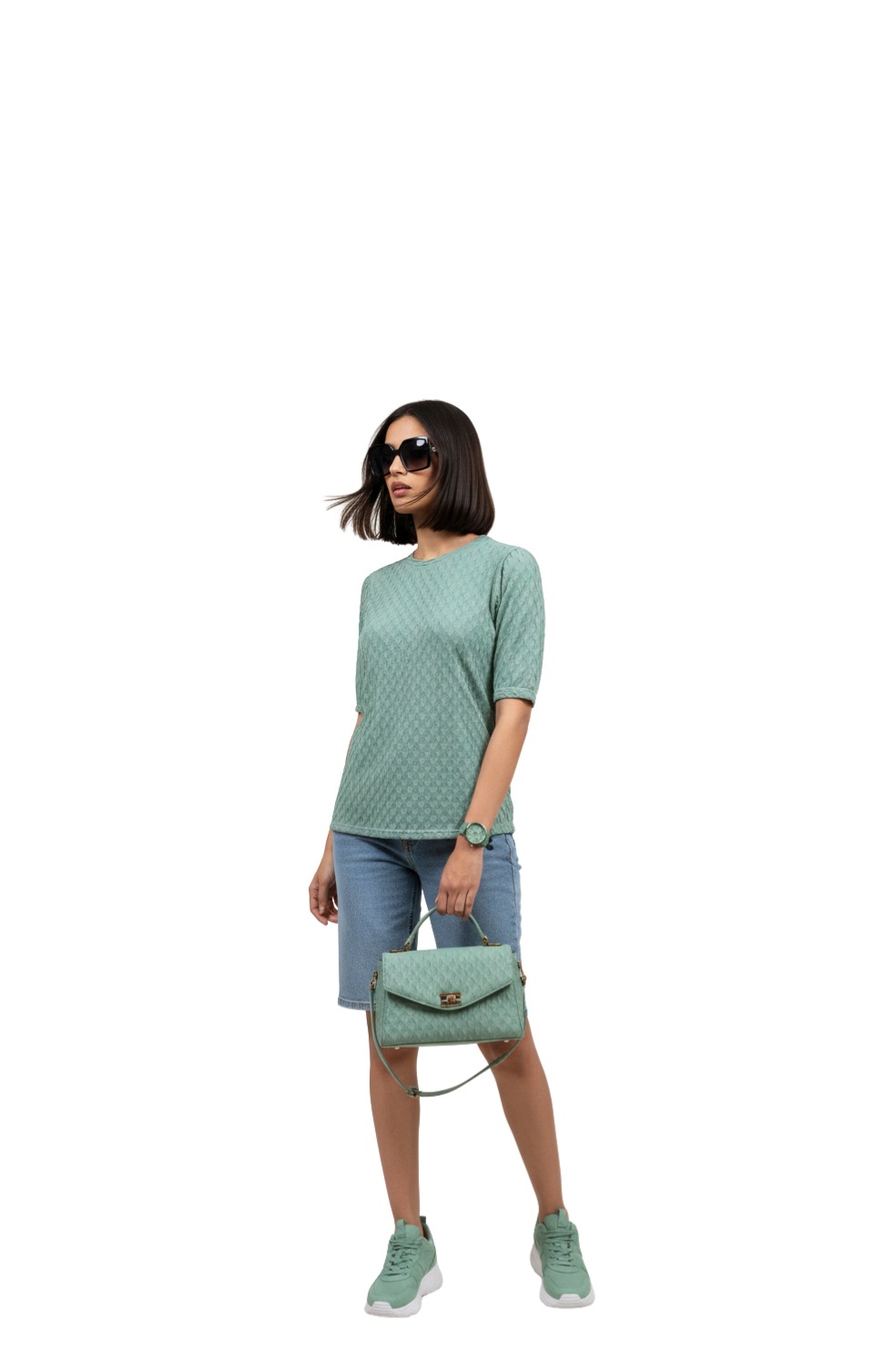 Woman wearing a green patterned top and shorts, holding a matching green handbag on a white background